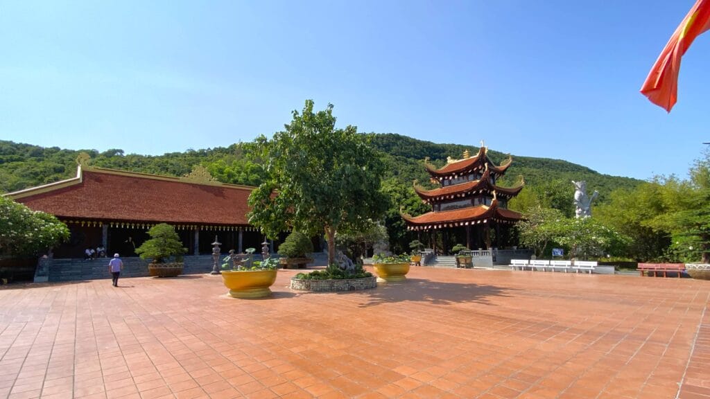 Sân gạch đỏ, bên trái là điện mái ngói đỏ, bên phải là lầu ba tầng mái cong