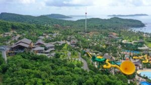 Hòn Thơm Phú Quốc nhìn từ trên cao, rừng xanh phủ đồi, ống trượt vàng và hồ bơi của công viên nước, tháp sọc trắng đỏ trên đỉnh, biển và các hòn đảo phía xa
