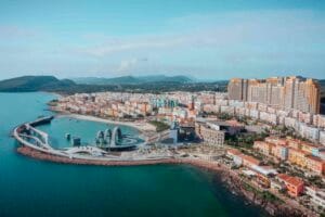 Thị trấn Hoàng Hôn nhìn từ trên cao: sân khấu vòm Kiss of the Sea bên bãi cát, cầu cong ra biển, dãy nhà nhiều màu