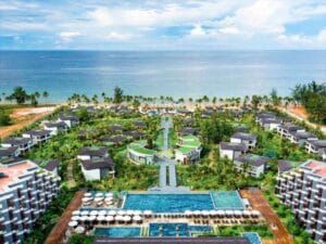 Dãy resort ven biển Phú Quốc nhìn từ trên cao: biệt thự mái xám giữa vườn cây, hồ bơi dài ở giữa, hàng dù trắng và biển xanh phía xa