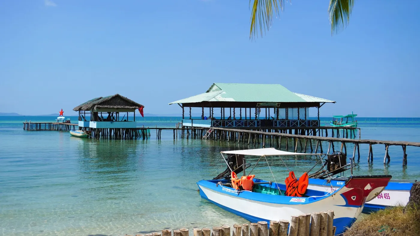 Cano có áo phao đậu cạnh nhà bè trên mặt nước trong