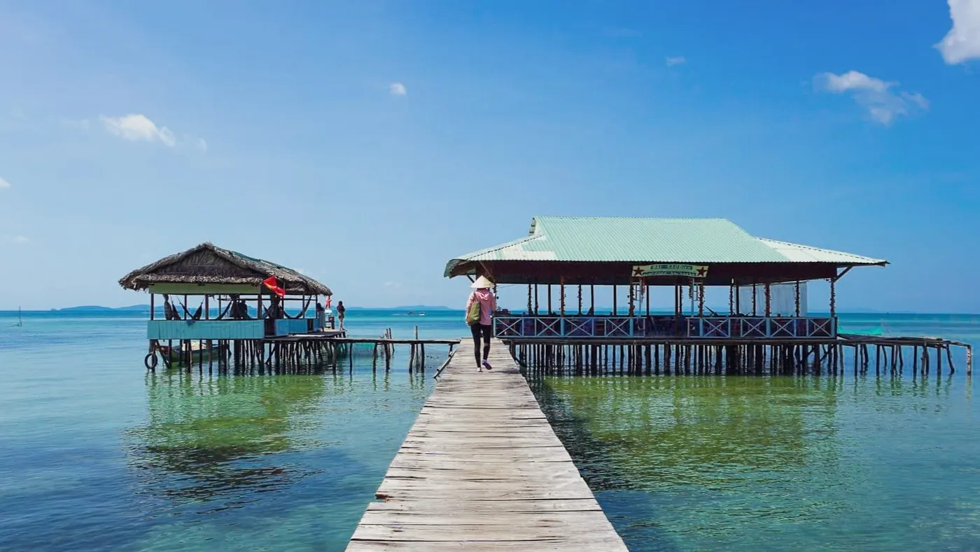 Cầu gỗ dài dẫn ra hai nhà bè trên mặt nước trong xanh